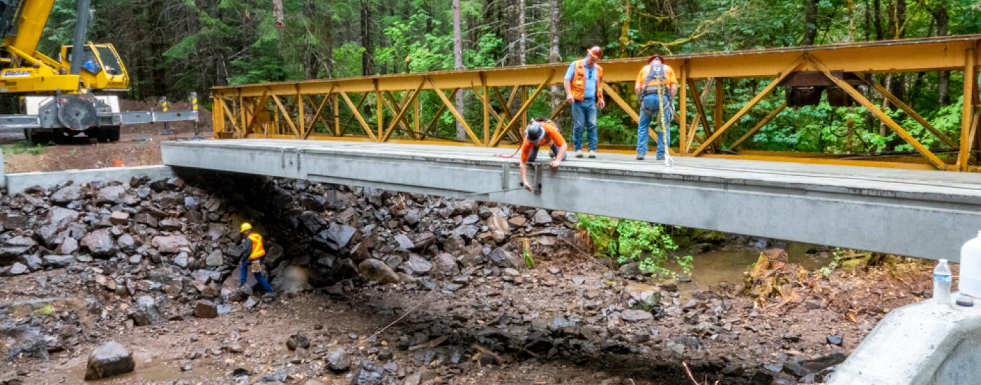 Workers insert a tie rod to help provide stabilization for the new bridge on Road 29 in the Umpqua National Forest's Tiller Ranger District