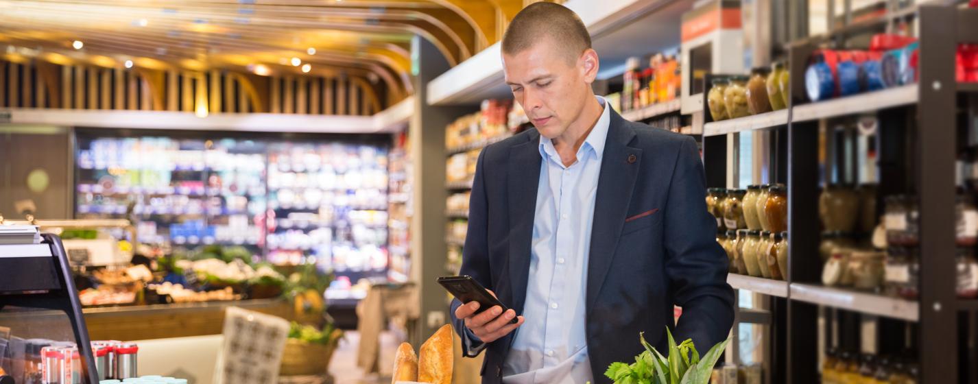 A person checking a phone with a shopping cart in a store
