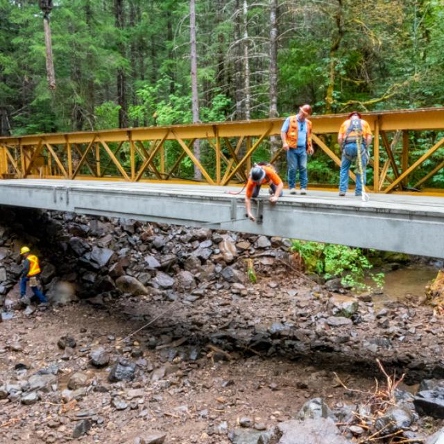 Workers insert a tie rod to help provide stabilization for the new bridge on Road 29 in the Umpqua National Forest's Tiller Ranger District