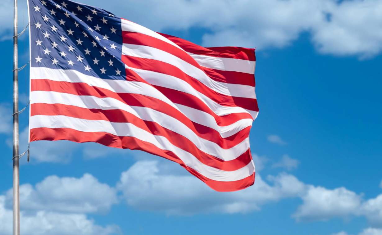 American flag waving with a blue sky in the background