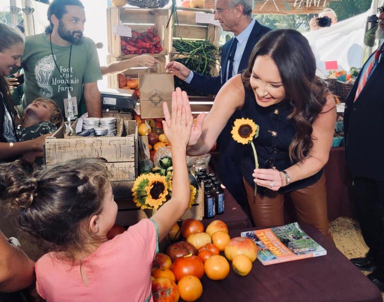 Secretary Rollins giving a high five to a girl at the farmers market