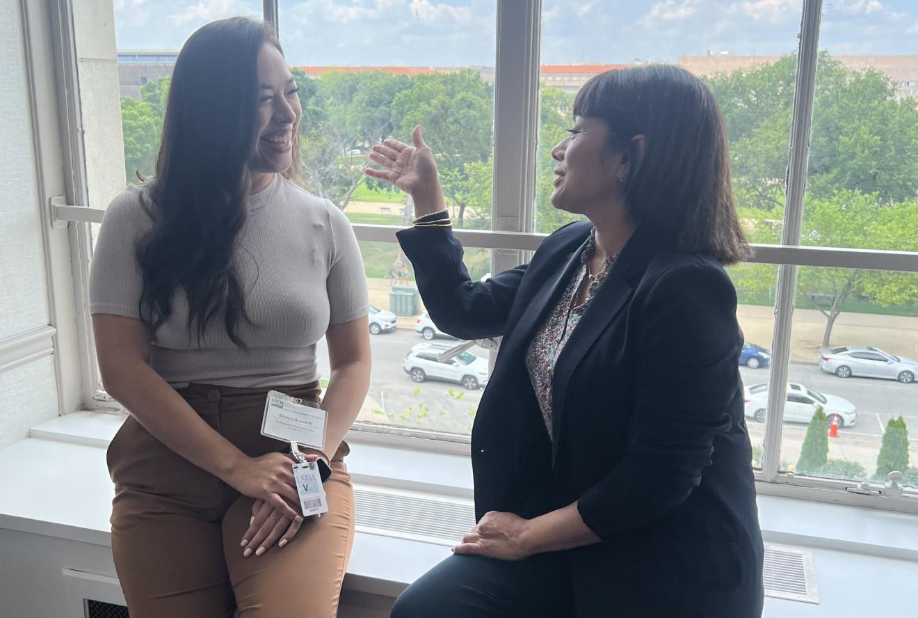 Two women speaking near a window